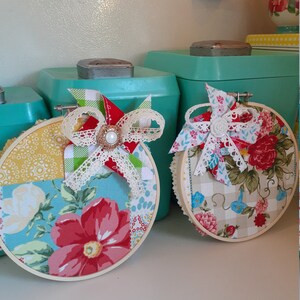 May include: Two handmade embroidery hoops with a patchwork design featuring floral patterns, gingham, and lace accents. The hoops are decorated with pinwheels and bows.