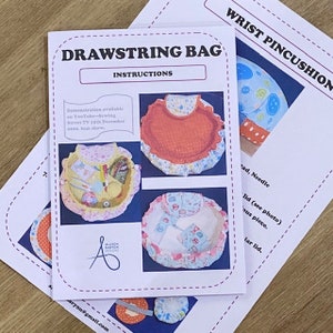 May include: Instructions for a drawstring bag sewing project. The instructions include a demonstration available on YouTube-Sewing Street TV on December 15th, 2010. The image shows three different drawstring bags with various fabric patterns.