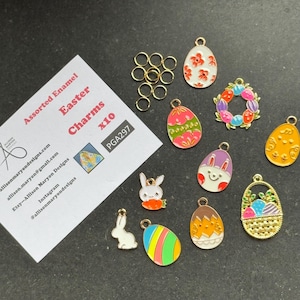 May include: A collection of assorted enamel Easter charms, featuring Easter eggs, bunnies, and a basket, in various colours. The charms are gold-toned and come with jump rings. The image also includes a card with the text "Assorted Enamel Easter Charms x10".