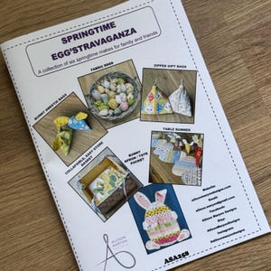 May include: A leaflet titled "Springtime Egg'stravaganza" displaying six springtime crafts. The items shown include fabric eggs in a basket, bunny sweetie bags, zipped gift bags, a collapsible basket, a table runner, and a bunny apron/tote pocket.