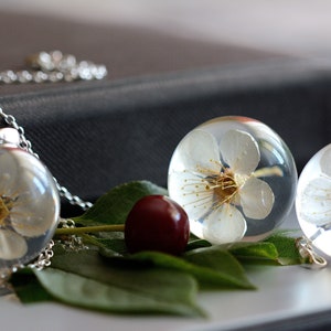 Pendant with natural white cherry flower (Prunus sp.) in the resin ball with sterling silver. Sphere 3 cm. WItchout chain.