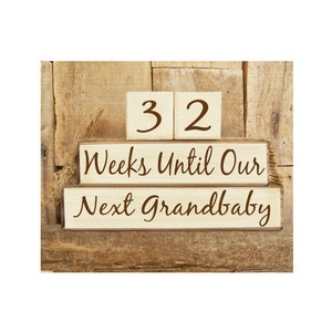 May include: Wooden blocks stacked on a rustic wood background. The top two blocks read "32" and the bottom two blocks read "Weeks Until Our Next Grandbaby".