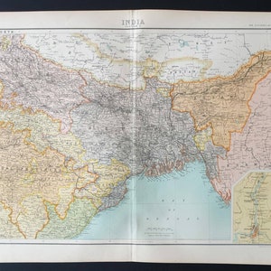 May include: A detailed vintage map of India, printed on aged paper. The map features a beige, brown, and green colour scheme, with the title "INDIA" at the top. Additional text and a smaller inset map are also visible.