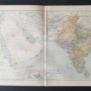 May include: A vintage map of India and the surrounding areas, showing detailed geographical features. The map is printed on aged paper, giving it a classic look, with various countries and seas in muted colours. The title "INDIA" is clearly visible.