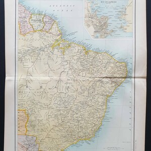 Peut inclure: Une carte ancienne de l'Amérique du Sud, avec des informations géographiques détaillées. La carte comprend l'océan Atlantique et une petite carte encadrée de Rio de Janeiro. La carte est imprimée sur du papier vieilli, avec le texte "SOUTH AMERICA" en haut.
