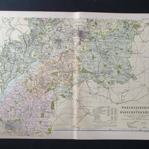 Op de afbeelding: Oude kaart van Worcestershire en Gloucestershire, Engeland, met gedetailleerde cartografie van wegen, steden en geografische kenmerken. De kaart is gedrukt op verouderd papier en heeft een vintage uitstraling, met een mix van kleuren en ingewikkelde details.