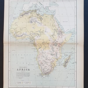 May include: A detailed vintage physical map of Africa, showing geographical features. The map uses beige, green, and pink hues to denote land elevations and terrains. The title "PHYSICAL MAP OF AFRICA" is printed at the bottom of the map.