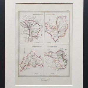 May include: Framed antique print showing four detailed maps of Barnstaple, Tiverton, Ashburton, and Dartmouth. Each map is outlined in red and green, with place names and roads. The print is mounted in a white mount.