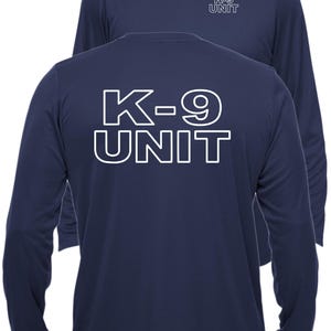 May include: Navy blue long-sleeve shirt with the text "K-9 UNIT" in white on the back and front. The shirt has a crew neck and is made of a smooth, likely athletic, material.