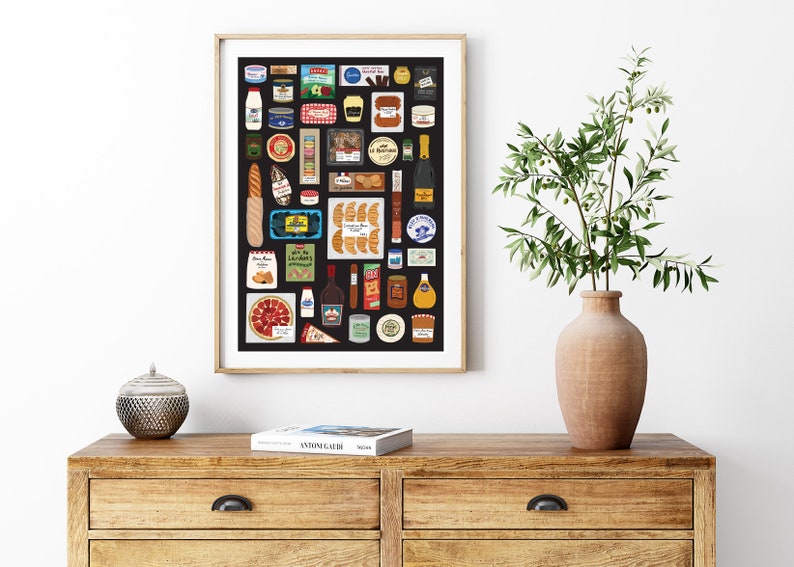 May include: A black and white illustrated poster of a variety of French foods and beverages, including bread, cheese, wine, and pastries. The poster is framed in a light wood frame and is hanging on a white wall.