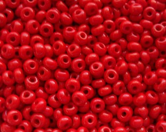 May include: A close-up image of a large quantity of small, red, round seed beads. The beads are arranged in a random pattern, creating a textured surface.