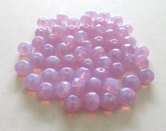 May include: A pile of light purple glass beads. The beads are round and have a slightly iridescent finish.