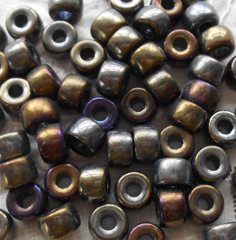 May include: A collection of small, round, iridescent beads in shades of gold and silver. The beads have a hole in the center for stringing.