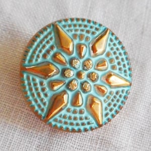One 18mm Czech glass button, with a gold raised star with a turquoise wash, verdigris look decorative shank button 05201
