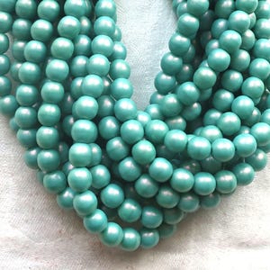 May include: A strand of turquoise blue wooden beads. The beads are round and have a smooth, polished finish.
