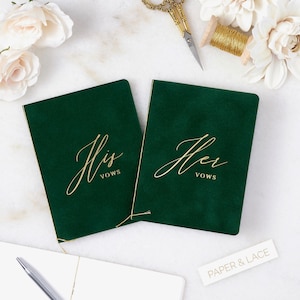May include: Two green velvet vow books with gold lettering. The book on the left says "His Vows" and the book on the right says "Her Vows".