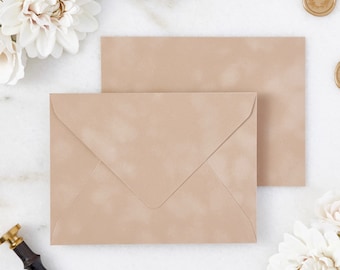May include: Two beige envelopes with a textured finish are displayed. The envelopes are positioned on a white surface, accompanied by white flowers, gold wax seals, and a label that reads "PAPER & LACE". A vintage wax seal stamp is also visible.