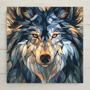 May include: A square wall art piece featuring a stylized wolf head rendered in a stained glass mosaic pattern. The design uses shades of deep blue, slate gray, and warm amber tones to create the fur, with two piercing orange eyes and a black nose.