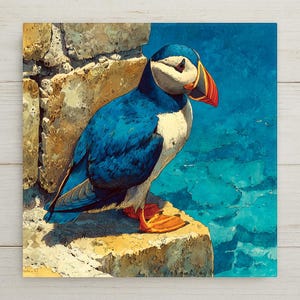 May include: A square canvas print featuring a vibrant illustration of a puffin bird. The bird has blue and white plumage, a large orange beak, and orange feet. It is perched on a rocky ledge with a turquoise ocean backdrop.