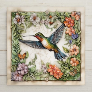May include: A square decorative tile featuring a central hummingbird in flight with iridescent green, blue, and orange plumage. The bird is surrounded by a relief border of green leaves, orange and purple flowers, and two small butterflies.