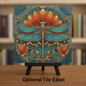 May include: A square decorative tile featuring a central dragonfly with intricate teal wings and a gold body, positioned against a stylized orange flower and teal background. The tile is displayed on a black stand with the text Optional Tile Easel.