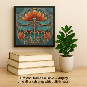 May include: A square framed wall art piece featuring a central teal dragonfly with intricate wings positioned over a large orange flower, surrounded by gold filigree accents on a blue background. The text reads: Optional frame available &mdash; display on wall or tabletop with built-in easel.