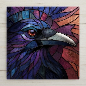May include: A square wall art piece featuring a stained glass style illustration of a raven head in profile. The bird has deep purple and blue feathers, a sharp silver beak, and a bright orange eye, set against a background of geometric glass shards.