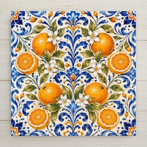 A balanced majolica spray of bright whole and halved oranges with white blossoms and green leaves in cobalt blue and warm orange-yellow on a soft cream tile.