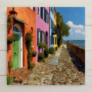 May include: A vibrant painting of colorful buildings along a cobblestone street. The buildings are painted in bright hues of orange, pink, blue, and yellow. Green doors and shutters add contrast. A brick walkway leads to a waterfront view under a blue sky.