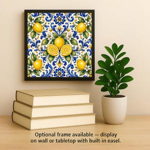 Puede incluir: Una pieza de arte mural cuadrada en un marco negro con un patr&oacute;n repetitivo de limones amarillo brillante, hojas verdes, flores blancas y complejos dise&ntilde;os de volutas en azul y blanco. La obra se muestra sobre una pila de tres libros.