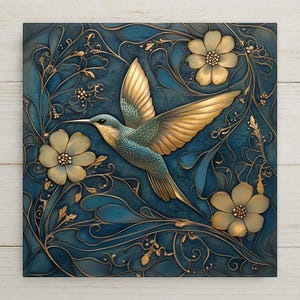 May include: A square wall art piece featuring a hummingbird in flight, rendered in a stylized art nouveau design. The bird has gold wings and a teal body, set against a teal background with gold floral and leaf accents.