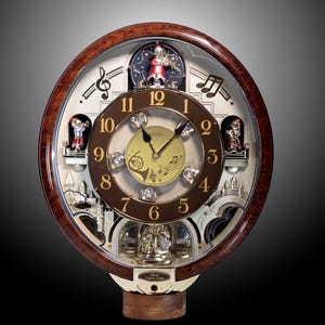 May include: A round Seiko wall clock with a dark wood frame, featuring a central gold dial with musical notes and a horn graphic. The clock face has brown numerals, three small figurines in red and white outfits, and a decorative castle base.
