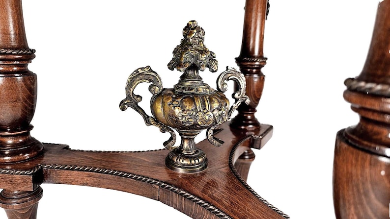 Puede incluir: Una mesa de madera con un remate decorativo de lat&oacute;n en el centro. La mesa tiene un acabado marr&oacute;n oscuro y detalles intrincados.
