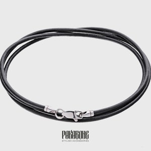 Puede incluir: Un collar de cuero negro con un cierre plateado. El collar est&aacute; hecho de dos hebras de cuero.