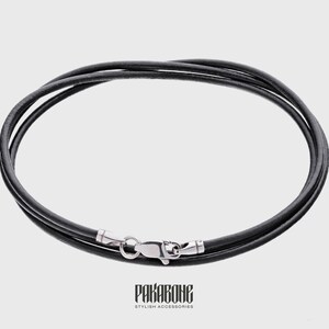 Peut inclure: Un collier en cordon de cuir noir avec un fermoir argent&eacute;.