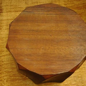 May include: A wooden octagonal tray with a smooth, dark brown finish. The tray is made of solid wood and has a natural grain pattern.