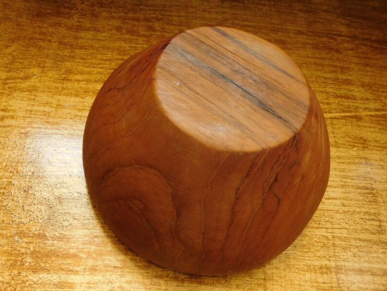 May include: A wooden bowl with a natural brown finish. The bowl is made from a single piece of wood and has a smooth, rounded shape.