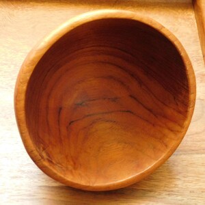 May include: A wooden bowl with a natural brown finish. The bowl is empty and has a smooth, rounded interior.