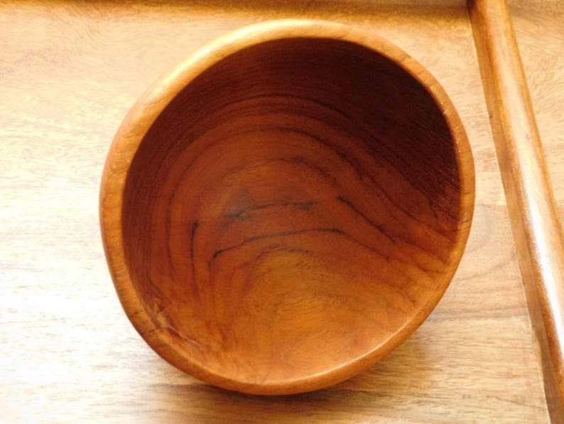 May include: A wooden bowl with a natural brown finish. The bowl is empty and has a smooth, rounded interior.