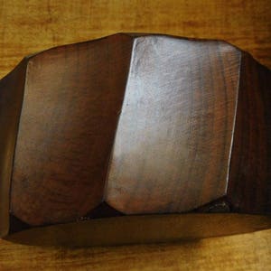 May include: A dark brown wooden bowl with a geometric shape. The bowl has a smooth, polished finish.