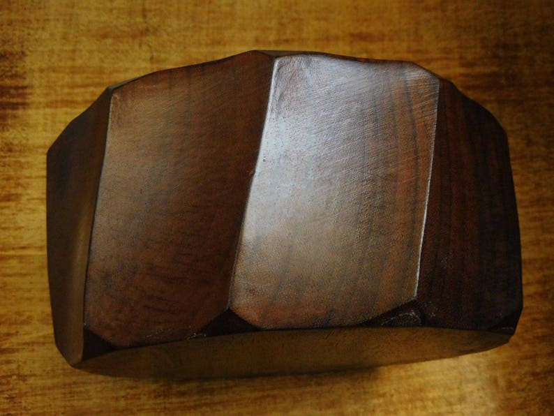 May include: A dark brown wooden bowl with a geometric shape. The bowl has a smooth, polished finish.