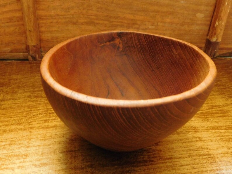 May include: A wooden bowl with a natural brown finish. The bowl is made of wood with a grain pattern.