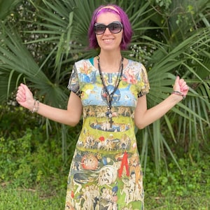 May include: A woman with purple hair and sunglasses is wearing a short-sleeved dress with a colorful print. The dress features a detailed scene with many figures and animals.
