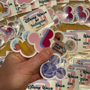 May include: A set of Disney Walls of Instagram stickers featuring various designs, including Mickey Mouse ears, a geometric pattern, and a floral design. The stickers are packaged in a clear plastic bag with a label that reads "Disney Walls of Instagram Starter Pack".