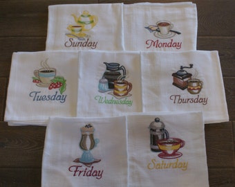 May include: Set of seven white tea towels with embroidered coffee-themed designs and the days of the week. The designs include a coffee pot, a coffee grinder, a cup of coffee, and a French press. The towels are embroidered with the words "Sunday", "Monday", "Tuesday", "Wednesday", "Thursday", "Friday", and "Saturday".