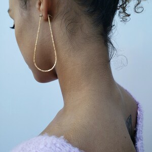 Puede incluir: Una persona con un su&eacute;ter de color morado claro y peludo con un arete de aro de oro en forma de l&aacute;grima en la oreja izquierda.
