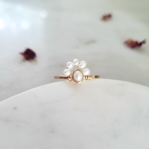 Peut inclure: Une bague en or avec un groupe de perles blanches, formant un d&eacute;licat motif floral.