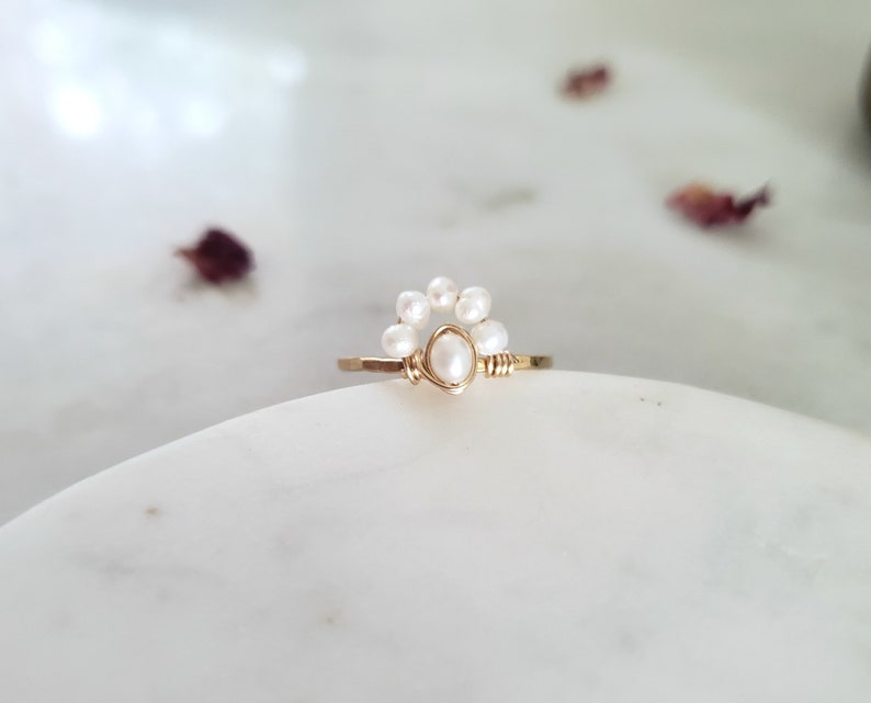 Peut inclure: Une bague en or avec un groupe de perles blanches, formant un d&eacute;licat motif floral.