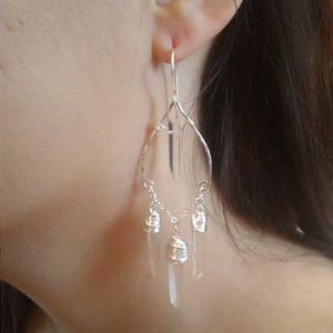 May include: Silver dangle earrings with three clear quartz crystal drops wrapped in silver wire.