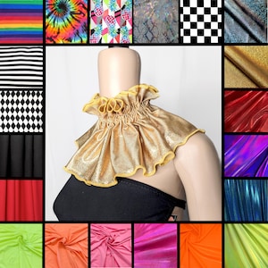 May include: A gold metallic ruffled neck collar featuring a gathered design with a yellow trim edge. The collar is displayed on a mannequin wearing a black strapless garment, surrounded by a grid of various fabric swatches in different colors.